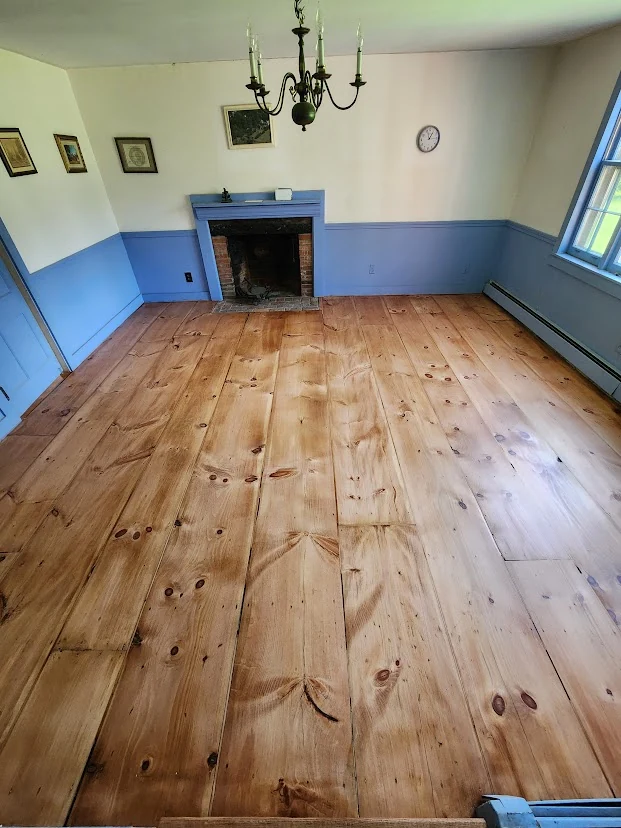 Wide-plank pine floor after sanding and refinishing in a fireplace room