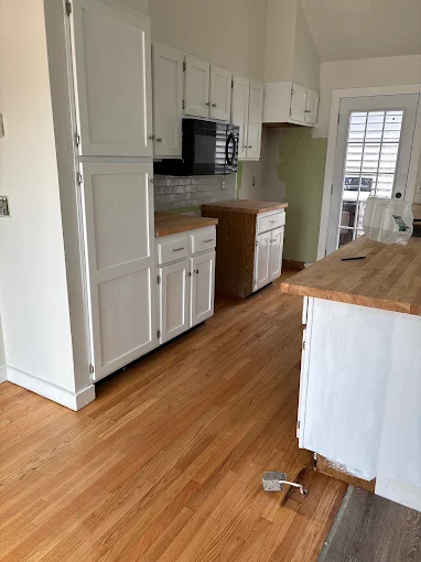 Finished hardwood flooring through a bright kitchen