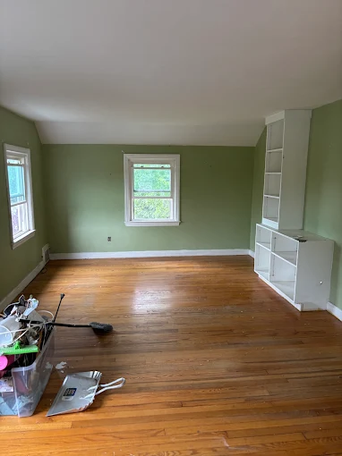 Worn hardwood floor in the room with built-in shelving before refinishing