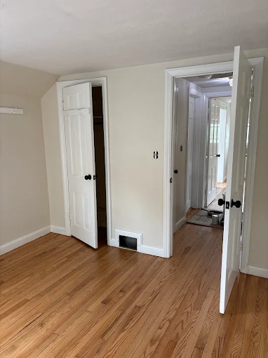 Finished hardwood flooring through a bedroom and adjoining hallway