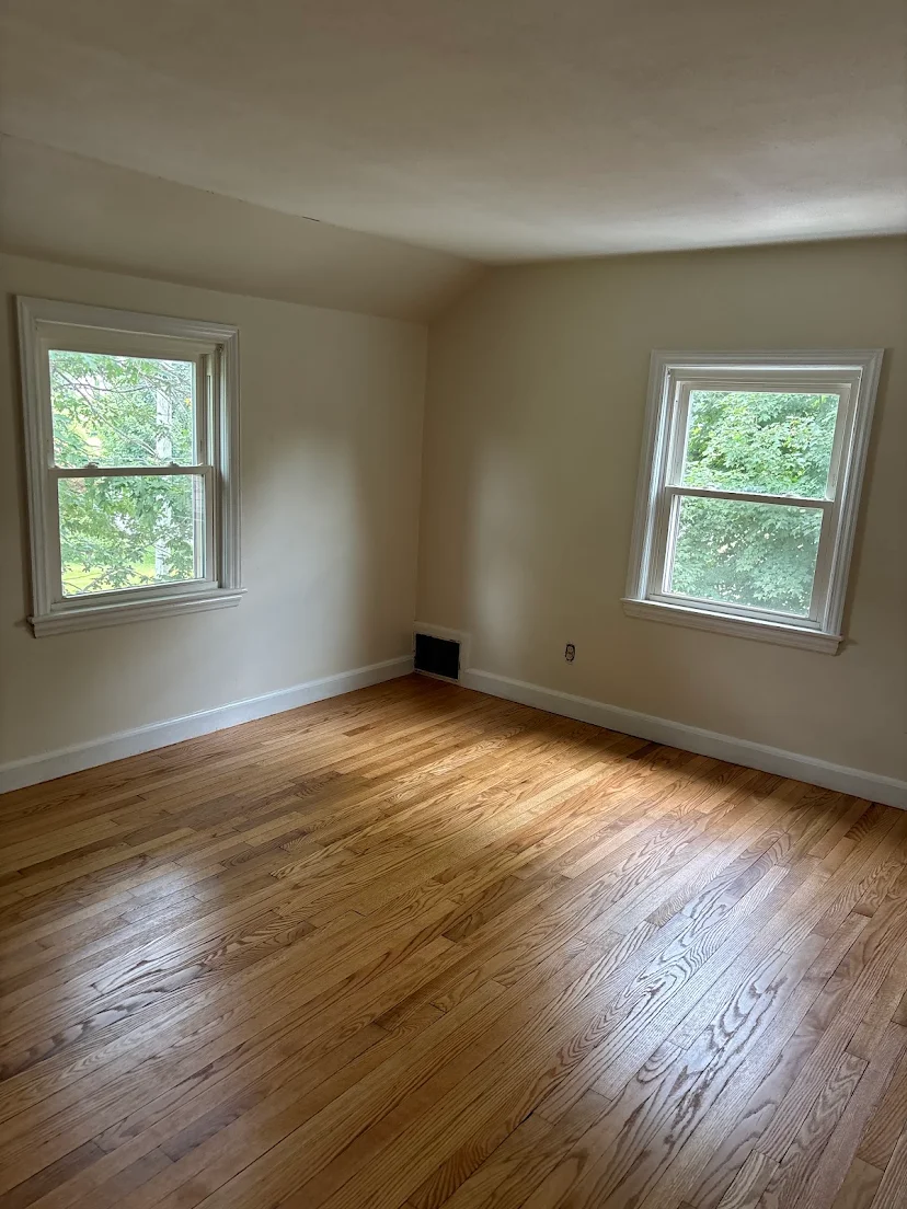 Finished hardwood floor in a bedroom with two windows