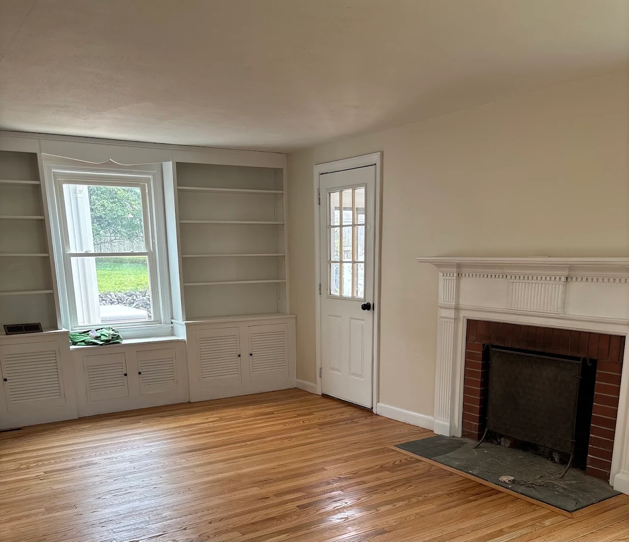 Finished hardwood floor in the living room with fireplace and built-in shelving