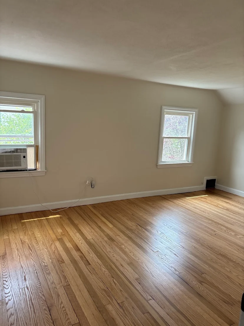 Finished hardwood floor in a bright room with two windows
